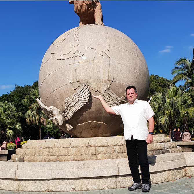 Graham standing in front of a globe showing Australia